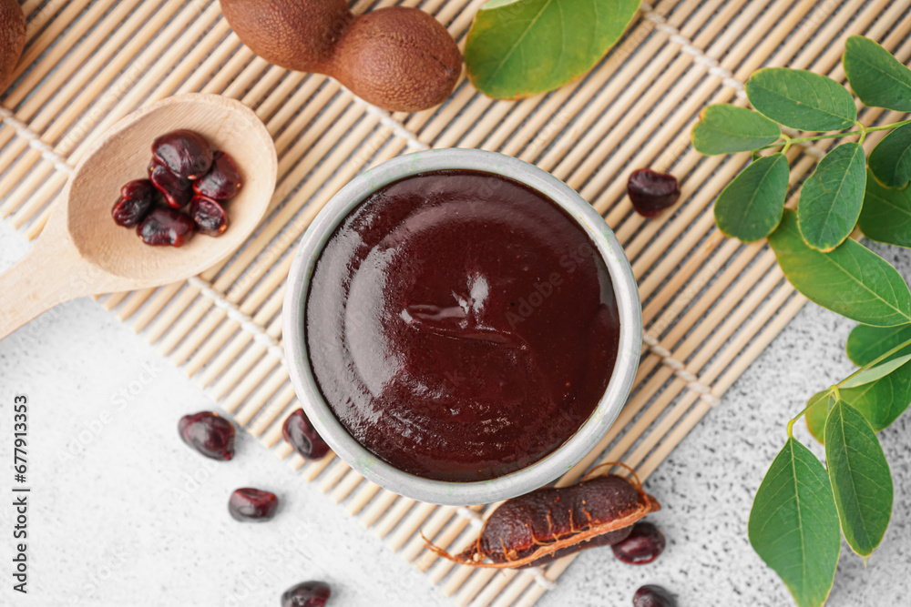 Bowl with tasty tamarind jam with fruits on white background