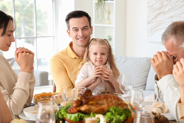 Poster - Happy family praying before dinner at festive table on Thanksgiving Day