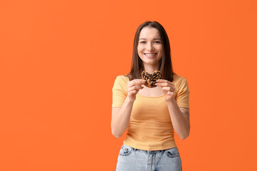 Canvas Print - Beautiful young woman with tasty cookie on orange background