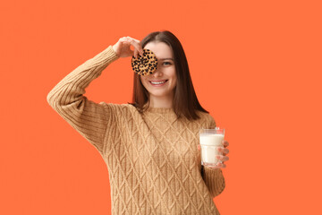 Canvas Print - Funny young woman with tasty cookie and glass of milk on orange background