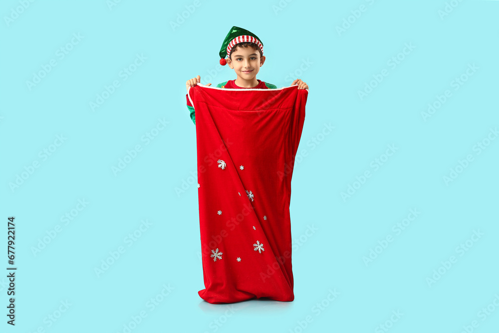 Cute little elf with Santa bag on blue background
