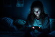 © MNStudio - Teenage girl checking her smartphone at night. Teen scrolling through social media on her phone screen. Internet addiction in kids.