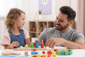 Canvas Print - Motor skills development. Father and daughter playing with stacking and counting game at table indoors