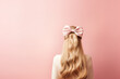 woman with bow in hair on pink solid background with copy space