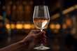 close up hand holding a wine glass in front of the luxury restaurant bokeh style background
