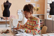 © Seventyfour - Pretty young female fashion designer sitting by electric sewing machine and creating new items for seasonal collection or upcycling old clothes