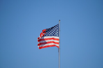 American Flag . USA national flag waving on wind against blue sky. Slow motion