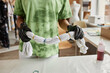 © Seventyfour - Cropped shot of young woman in protective gloves holding wet t-shirt bound with elastic bands over table before tie dye process