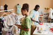© Seventyfour - Side view of young African American woman choosing tie dyed t-shirt while standing in front of rack with group of items hanging in row
