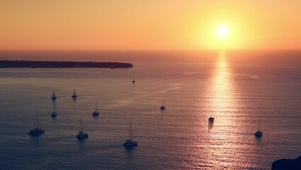 Wall Mural - Beautiful sunset at Santorini island, Greece. Yachts in the sea at sunset. Travel and summer vacations concept. Zoom out