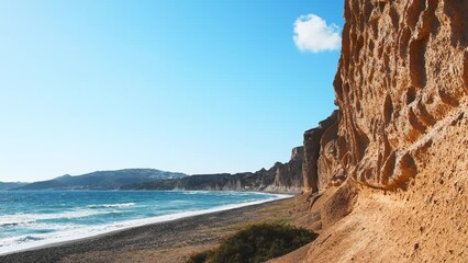 Wall Mural - Santorini island, Greece. Yellow pumice volcanic cliffs on Vlichada beach. Blue sea and the blue sky. View of the beach with volcanic sand at sanset. Summer landscape. Zoom out
