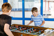© Irina Schmidt - Two smiling school boys playing table soccer. Happy excited children having fun with family game with siblings or friends. Positive preteen kids or teenager.