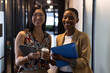 © Wavebreak Media - Portrait of happy diverse female colleagues with coffees, tablet and paperwork smiling in corridor