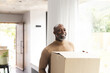 © Wavebreak Media - Happy african american mature man carrying packing box into new home, copy space