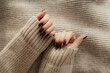 Stylish fashion women's brown manicure. Nails on the background of a knitted sweater.