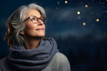 Wall Mural - Portrait of a content woman in her 50s dressed in a warm wool sweater against a sparkling night sky. AI Generation