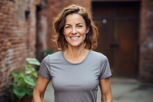Portrait Of A Grinning Woman In Her 40s Sporting A Technical Climbing Shirt Against A Vintage Brick Wall. AI Generation