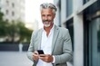 © Hope - Mature smiling man on glasses standing with cell phone in front of a new house . A real estate agent offers his services in buying and selling homes