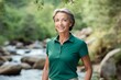 Portrait of a satisfied woman in her 50s wearing a breathable golf polo against a tranquil forest stream. AI Generation