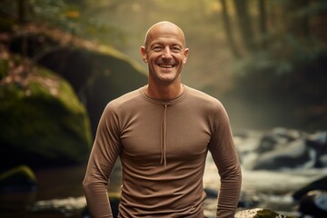 Wall Mural - Portrait of a joyful man in his 40s showing off a thermal merino wool top against a tranquil forest stream. AI Generation