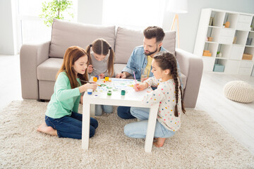 Sticker - Full body portrait of four persons man spend free time with cute positive girls painting sit on carpet behind desk indoors