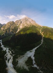 Wall Mural - Vertical photo, Aerial view of the stormy flow of the Dolra River, in the middle of a forest and high Caucasian mountains. way to Ushba mount, a hiking trail, a tourist route. Svaneti, Georgia