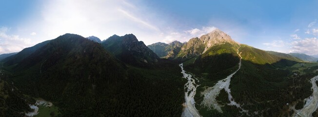 Wall Mural - Ultra wide aerial panorama with high resolution of The stormy flow of the Dolra River, in the middle of a forest and high Caucasian mountains Ushba, a hiking trail, a tourist route. Mazeri, Georgia