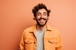 © CogniLens - Portrait of a happy man in his 20s sporting a rugged denim jacket against a pastel orange background. AI Generation