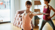 © Flamingo Images - Young woman doing the warrior pose in yoga class