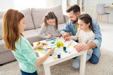 Poster - Photo of four people satisfied handsome guy sit with adorable positive girls on carpet painting free time indoors