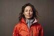 © CogniLens - Portrait of a merry woman in her 40s wearing a functional windbreaker against a minimalist or empty room background. AI Generation
