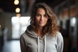 Portrait of a satisfied woman in her 30s wearing a zip-up fleece hoodie against a empty modern loft background. AI Generation