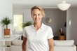 © CogniLens - Portrait of a grinning woman in her 40s wearing a sporty polo shirt against a crisp minimalistic living room. AI Generation