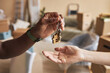 © Seventyfour - Hand of young African American male real estate agent passing key to new owner of apartment against furniture covered with cellophane