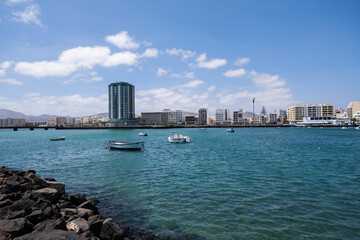 Wall Mural - View of the city of Arrecife from the Fermina islet. Turquoise blue water. Sky with big white clouds. Seascape. Lanzarote, Canary Islands, Spain.