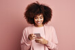 © Georgii - Cheerful shopper in pink t-shirt pays for fashion goods with credit card while ordering online. Stylish model shopping online on mobile phone while standing in studio