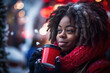 Beautiful black woman with dreadlocks drinking coffee from red cup in winter Christmas market