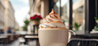 An appetizing cup of cappuccino with a pile of foam and cinnamon on the table of a city cafe against the background of a city street. A cozy pleasure, a walk