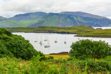 Isle Of Canna In The Inner Hebrides, Scotland.  A Tranquil Harbour With Moored Yachts And The Larger Isle Of Rum In The Background.  Horizontal.  Copy Space.