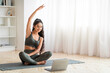 © Prostock-studio - Fitness at home: Woman stretches with laptop