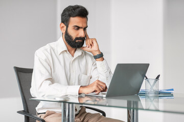 Poster - Serious indian businessman working on laptop at office