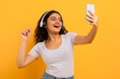 Adorable joyful young woman listening to music, taking selfie