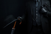Portrait Of British Businessman In Dark Suit Holding Umbrella And Bowler Hat. Mafia Hitman Or Gangster.