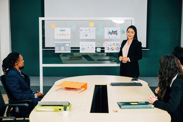 Wall Mural - Businesswoman expert in finance and marketing, leads seminar in office conference room. She explains innovative e-commerce strategy, encouraging discussion, cooperation, diversity among colleagues.