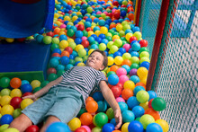 Young Boy Enjoying A Colorful Ball Pit At An Indoor Playground