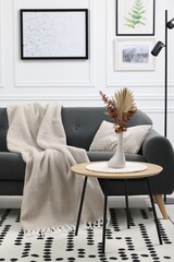 Poster - Stylish living room interior with comfortable sofa, blanket and side table