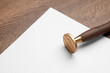 One stamp tool and sheet of paper on wooden table, closeup. Space for text