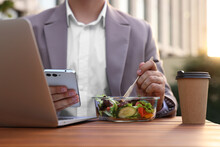 Businessman Using Smartphone During Lunch At Wooden Table Outdoors, Closeup