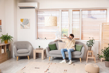 Poster - Young man turning on air conditioner at home