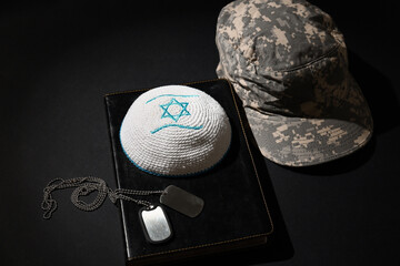 Wall Mural - Jewish hat with dog tags, Torah and military cap on dark background